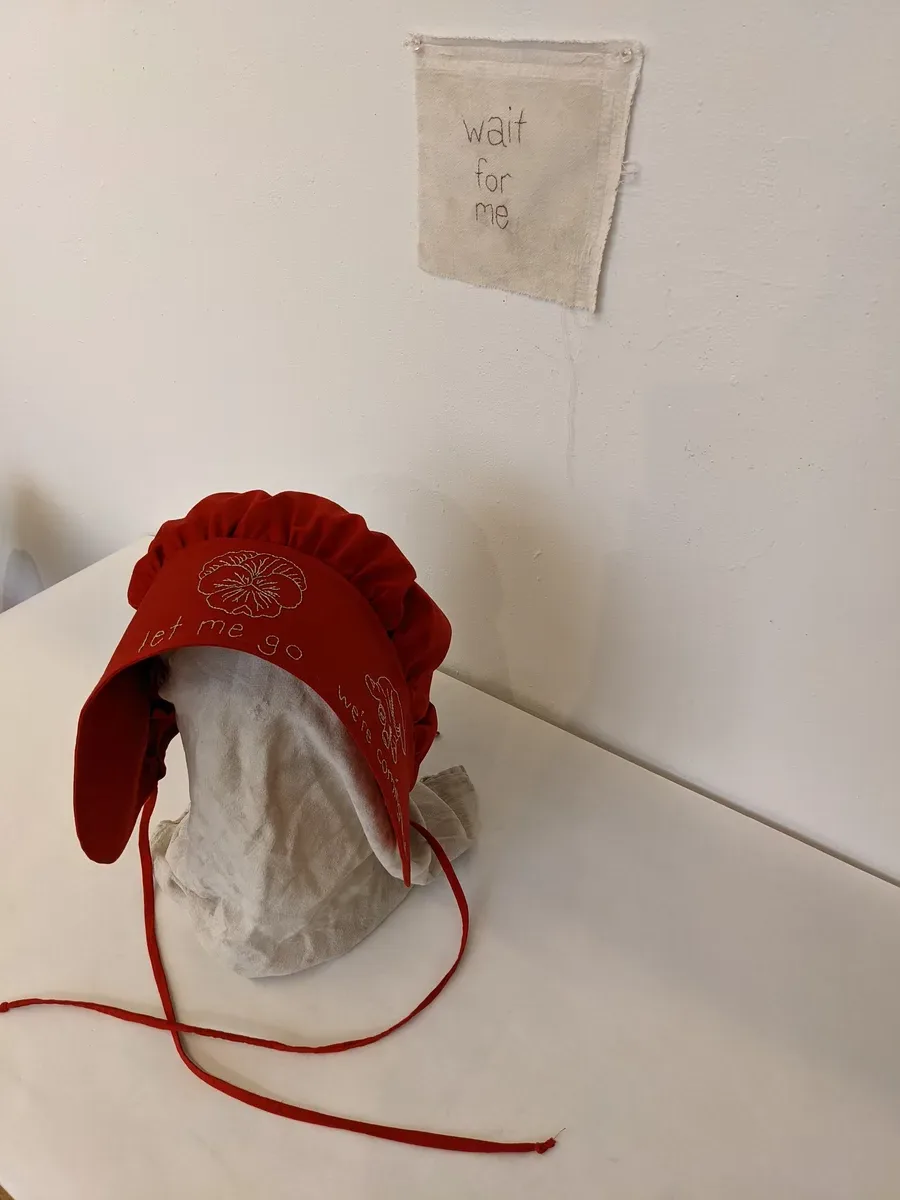 Mourning Bonnet — red bonnet with embroidery reading "let me go, we're coming"