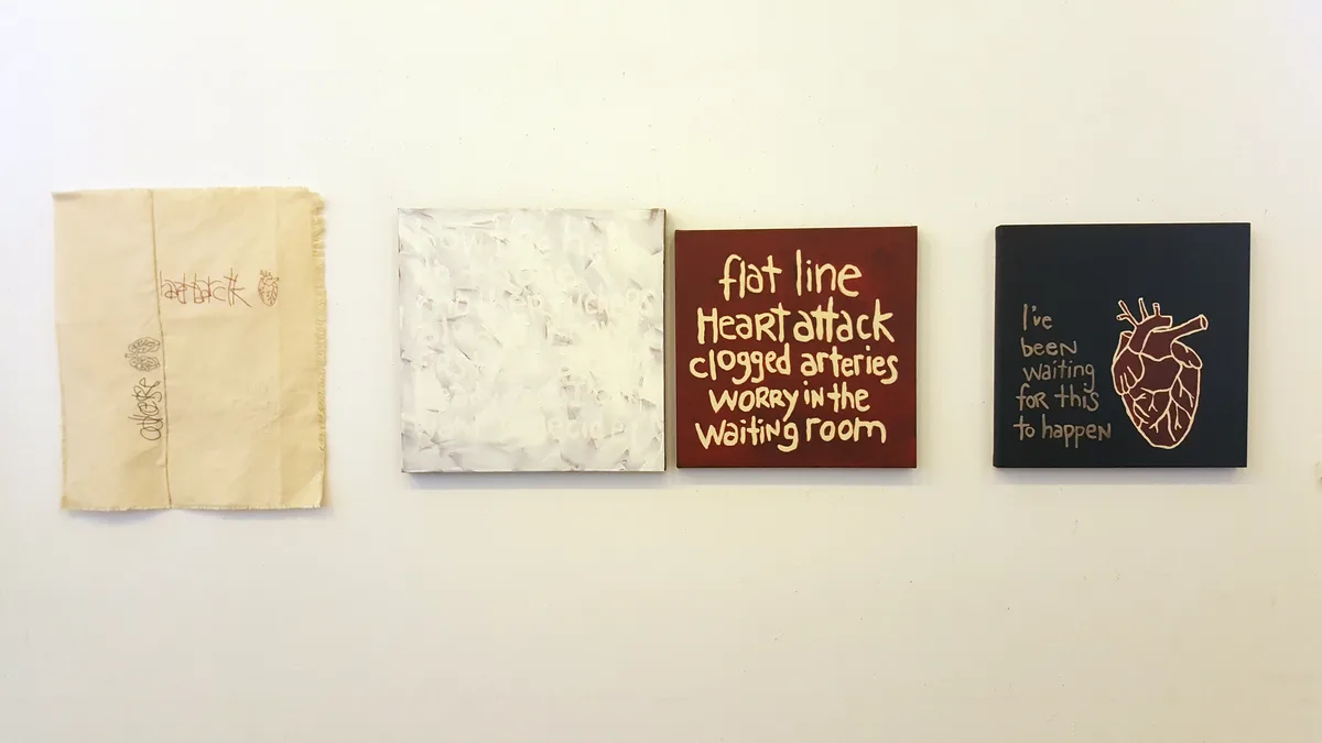 Installation view of four works on a gallery wall including raw canvas, text paintings, and anatomical imagery